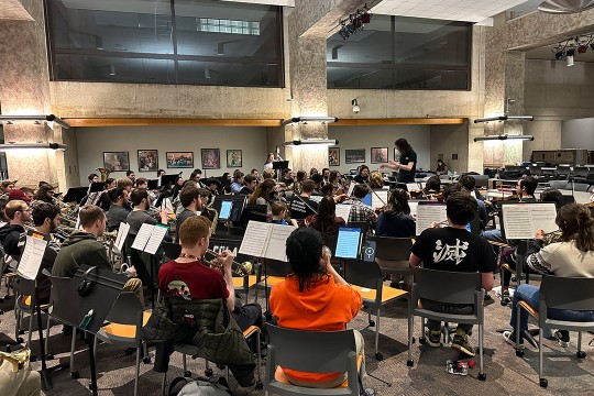 RIT’s Game Symphony Orchestra is shown rehearsing in a performance room.