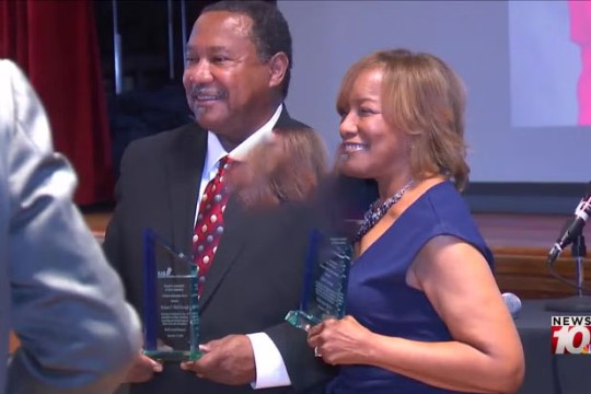a man and a woman recieve an award on stage