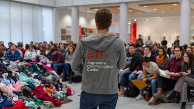 a photo of a male student speaking in front of a large group