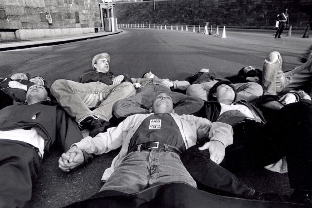 A photo taken from the exhibition which features a group of men and women laying down in the street with their arms and legs locked together in protest.
