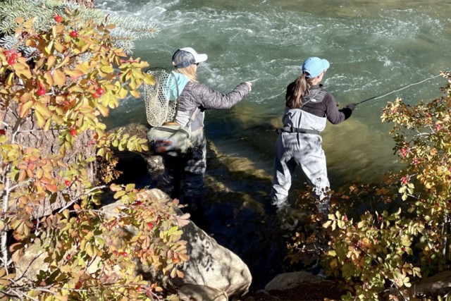 two women fly fishing in a river.