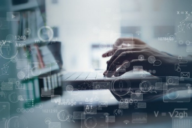 Hands type on a laptop keyboard.
