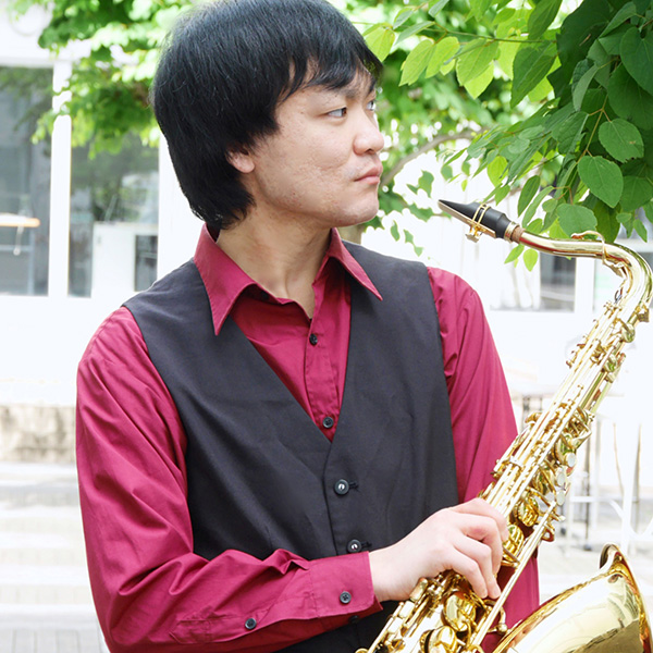 Akira Takeuchi posing with a saxophone.