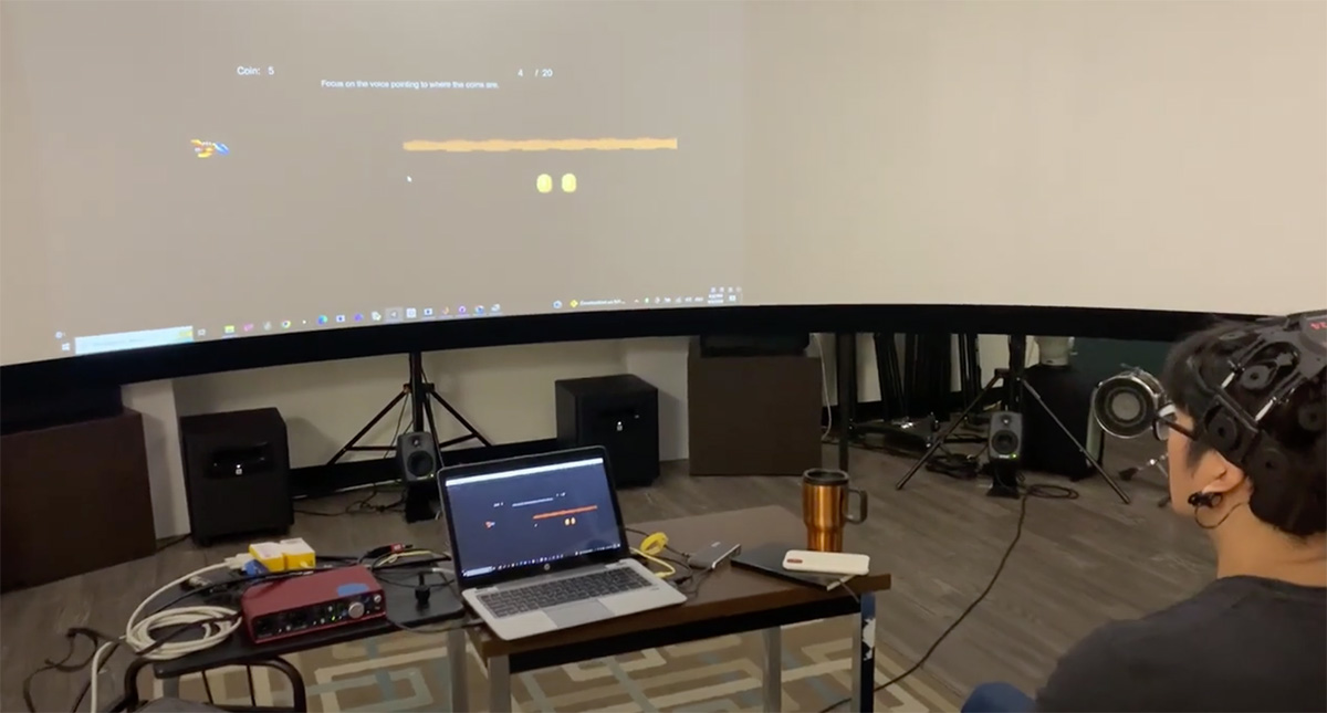 A faculty member sitting in front of a large curved screen.