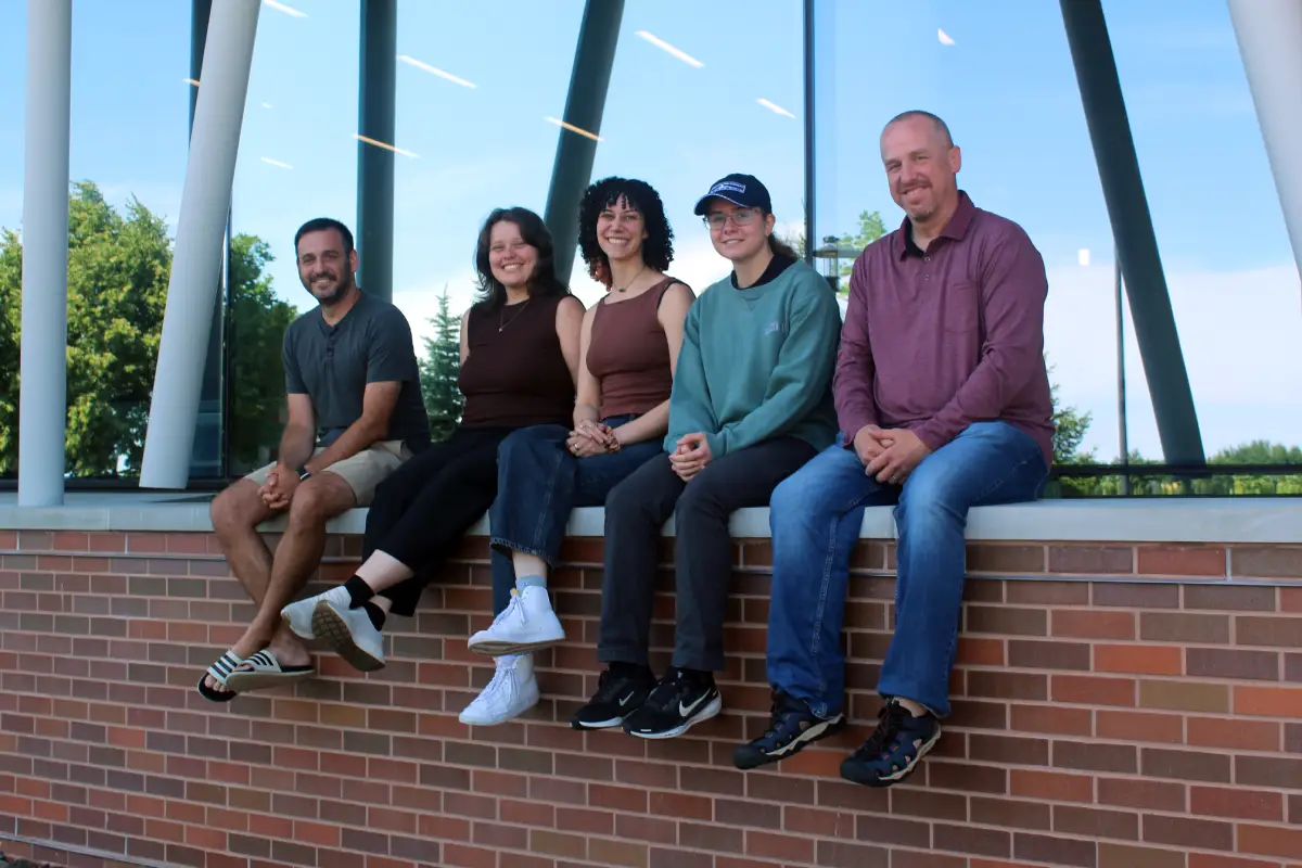 Character Mosaic team smiling while sitting on a brick half wall