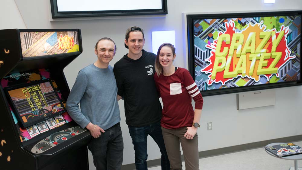 Crazy Platez team members pose for a photo in front of a framed picture of Crazy Platez