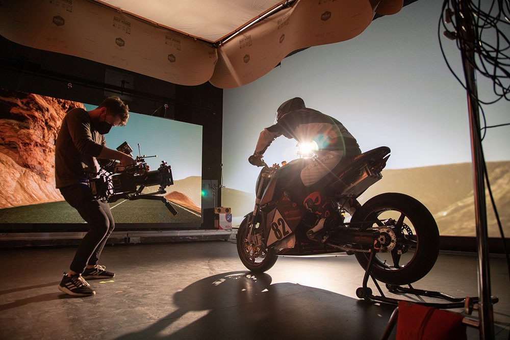 Camera man capturing a shot of someone on a stationary motorcycle with a virtual background
