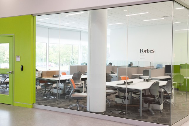 Glass room with lime-green door and several workstations with tables and chairs