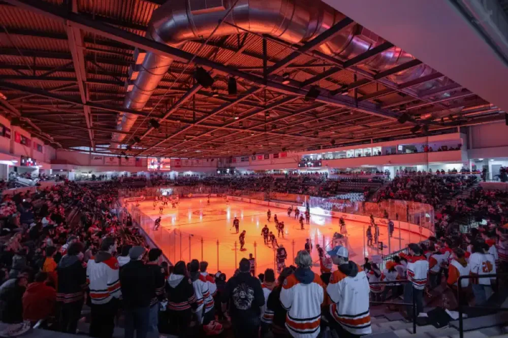 hockey players warming up in a dark arena with an orange light on the ice