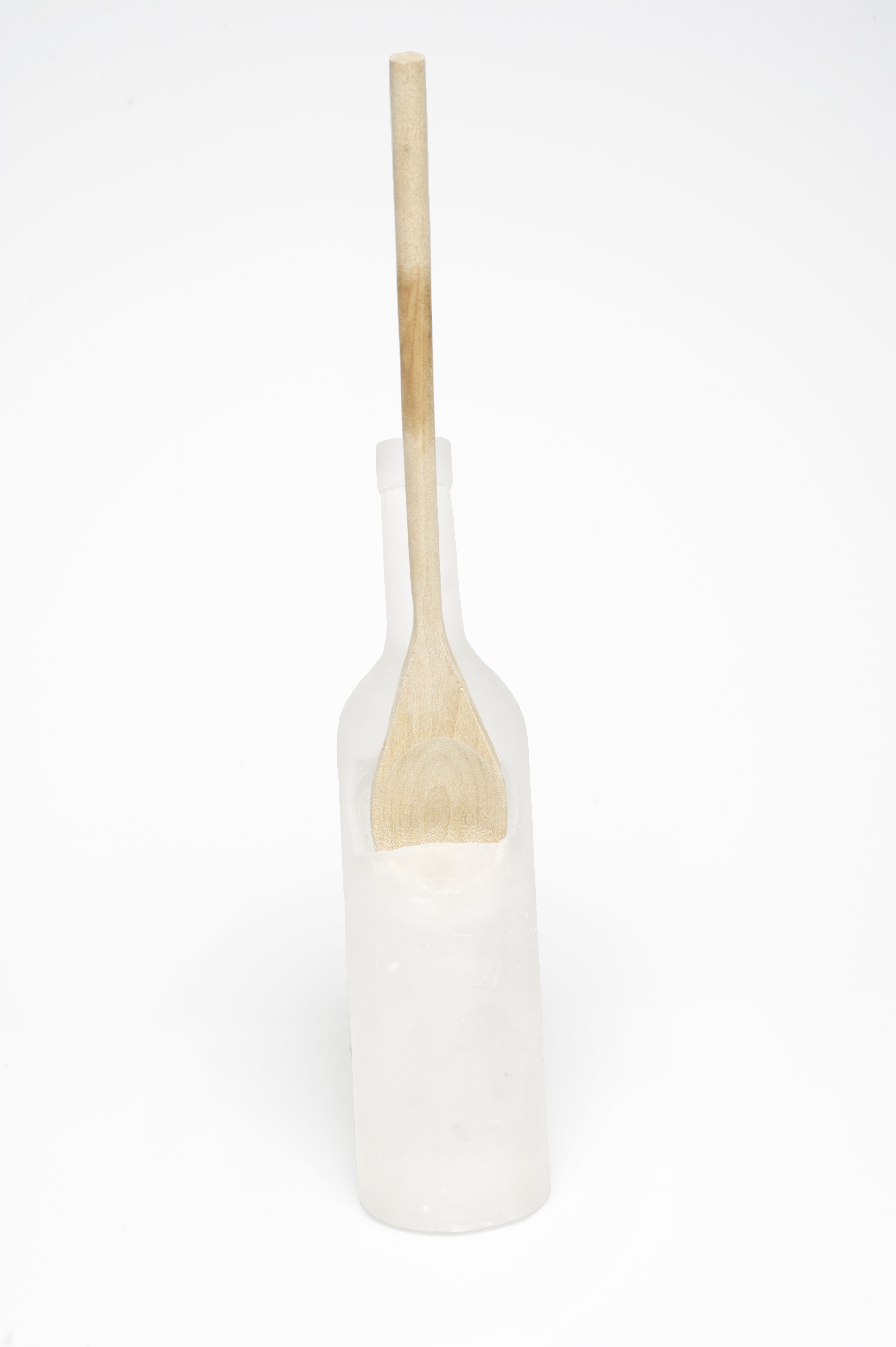 Spoon rest in a wine bottle shape holding a wood spoon.
