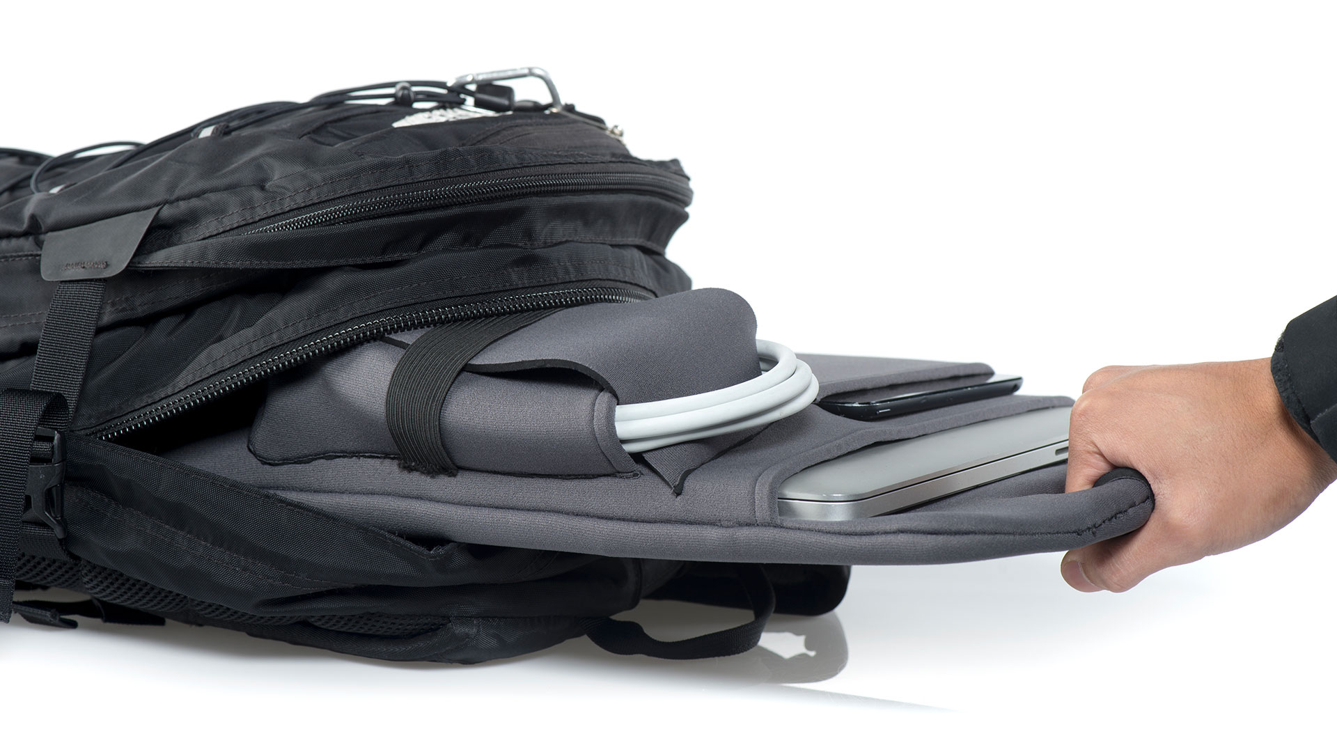 Close up of someone pulling backpack organizer by handle out of black backpack, all accessories in place