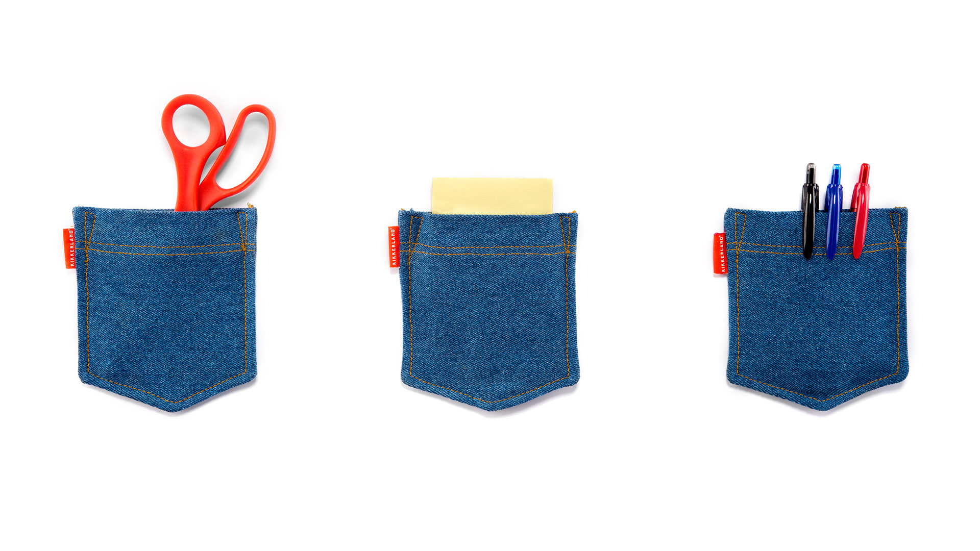 Three blue denim wall pockets side by side with assorted items tucked inside including scissors, notepad and pens 