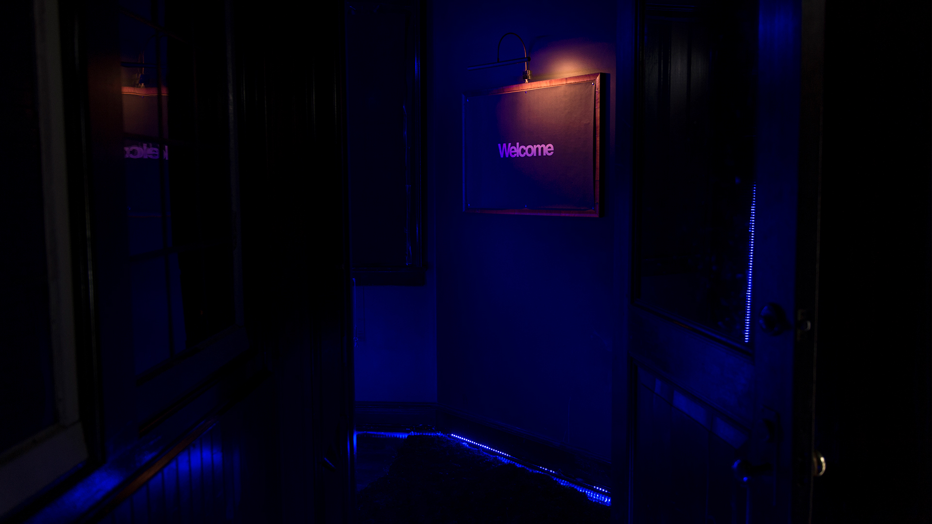 Dark entryway with deep blue lighting and Welcome sign on wall