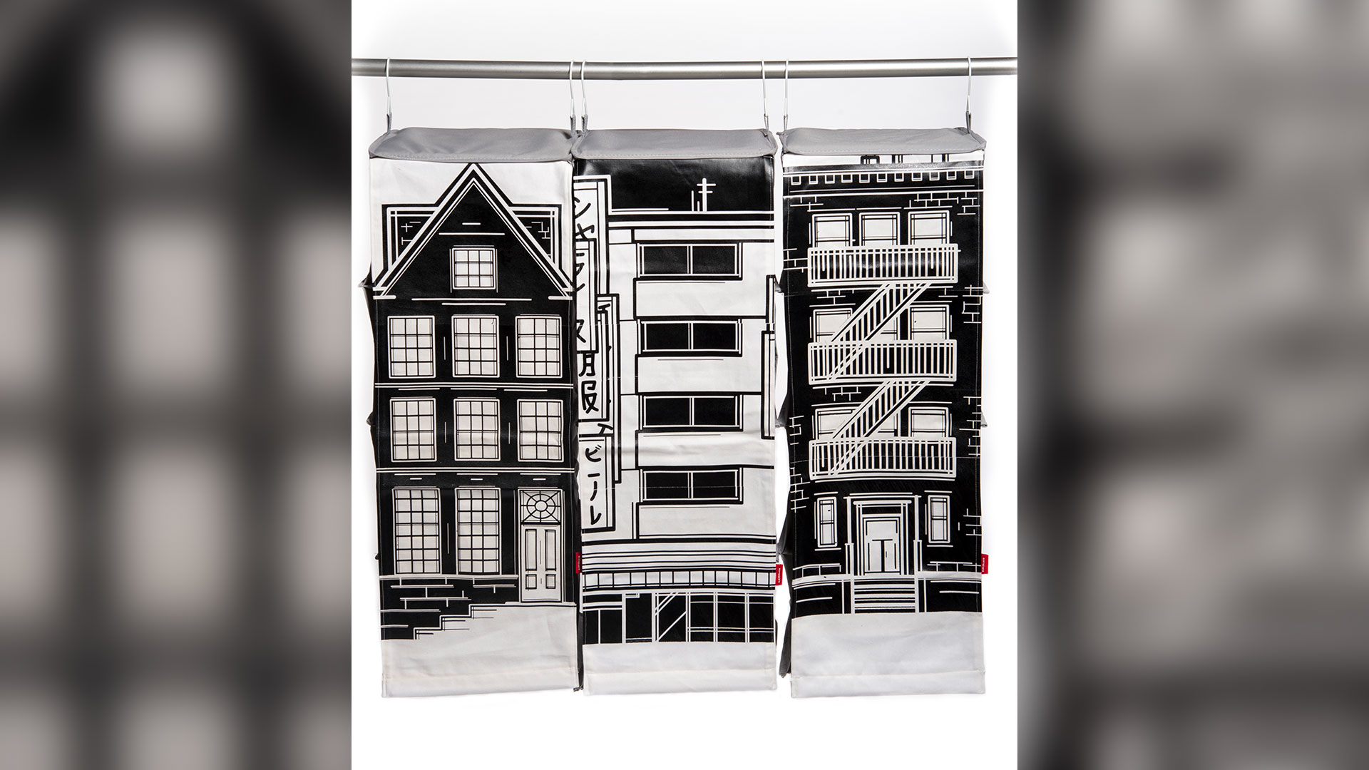 Front view of a series of 3 closet organizers hanging on long pole, each designed to look like city building facades in black and white
