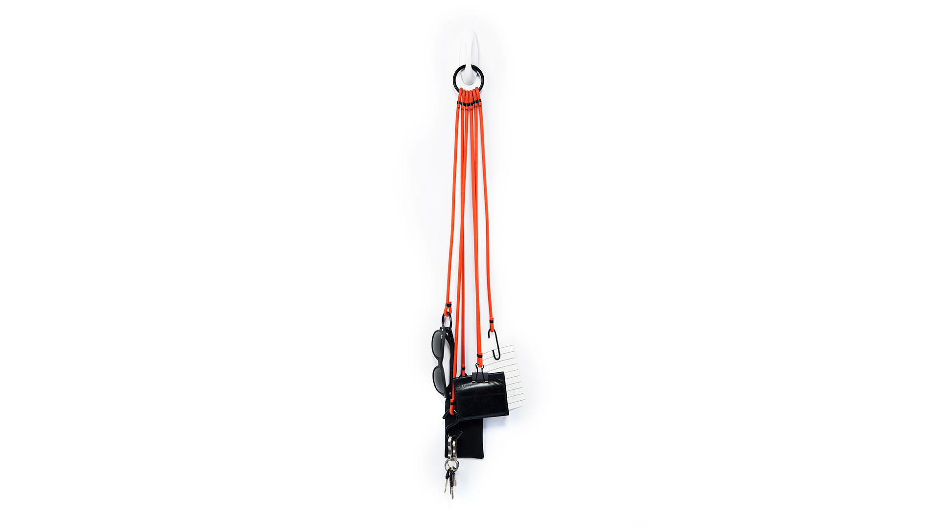 Various accessories (keys, wallet sunglasses etc) attached to five bright red-orange cords that are on wall hook with single black ring