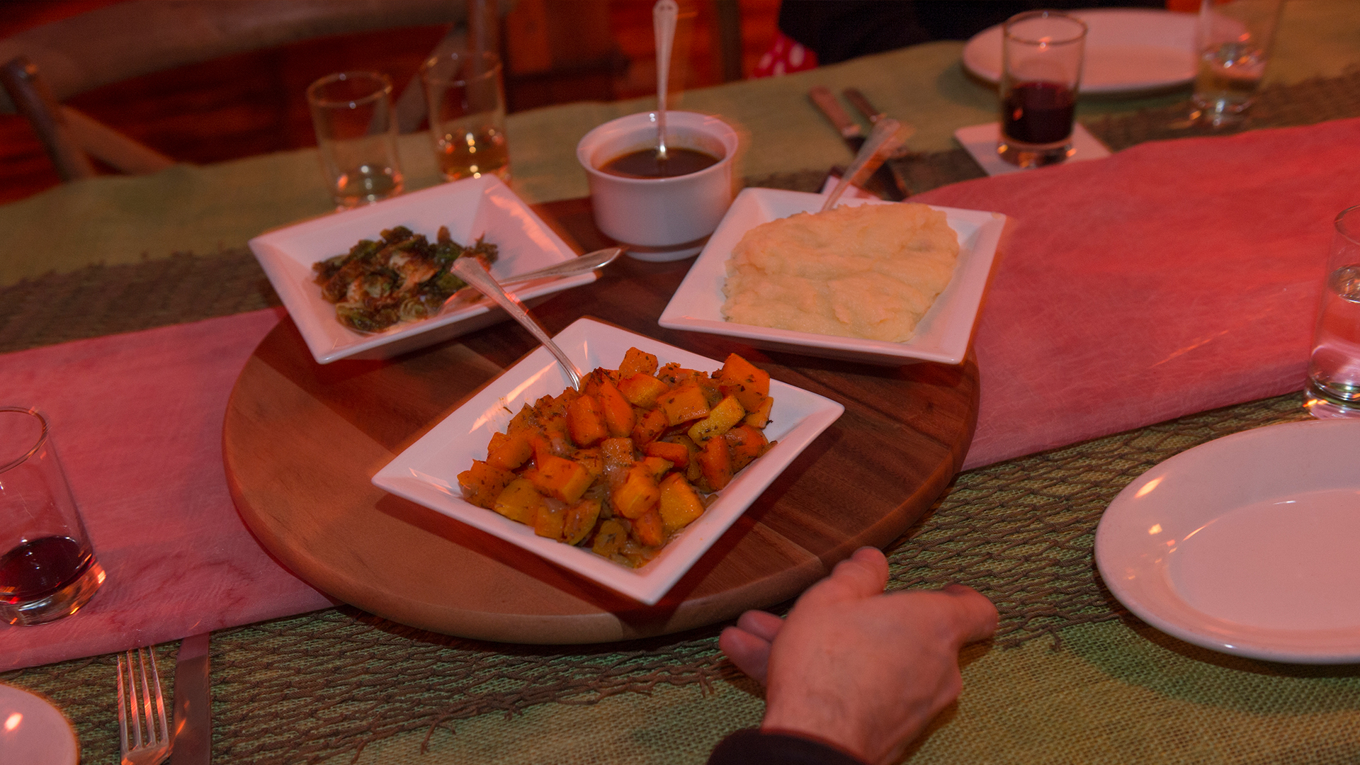 3 square bowls with assorted food on top of wooden circle platform on table