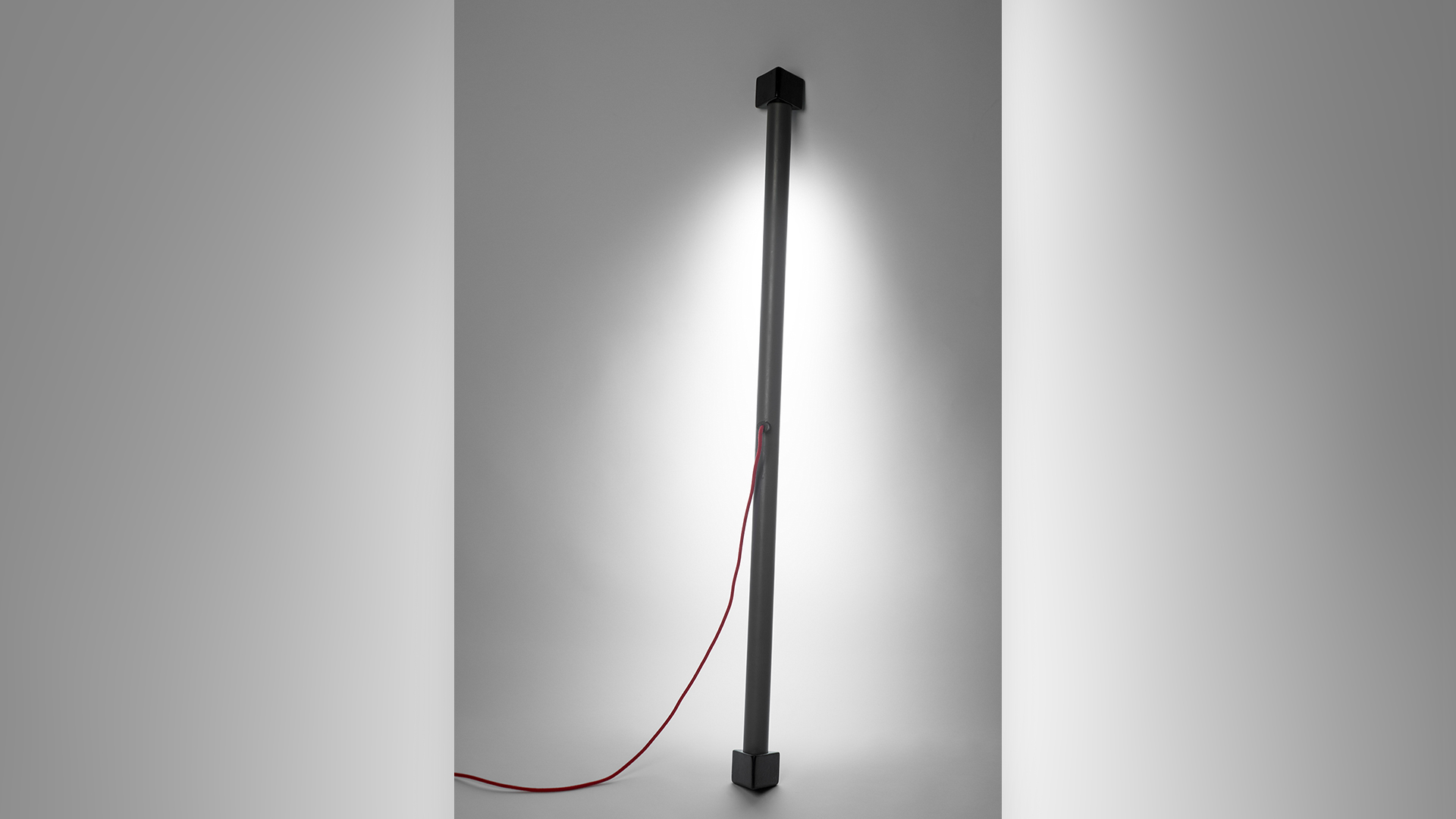 Vertical light with small space, light emanating from long lamp pole facing toward back wall