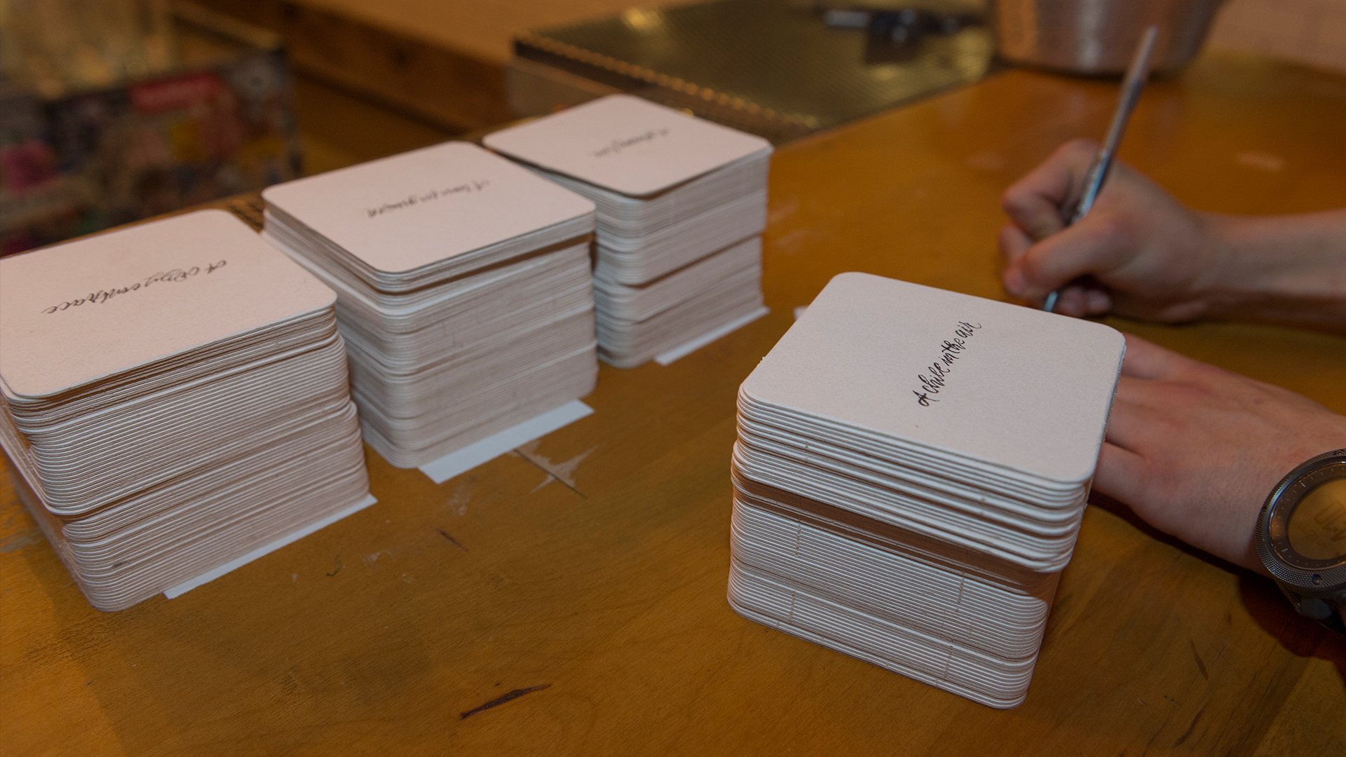 Three large stacks of white square coasters with "A Chill in the Air" in lettering on center