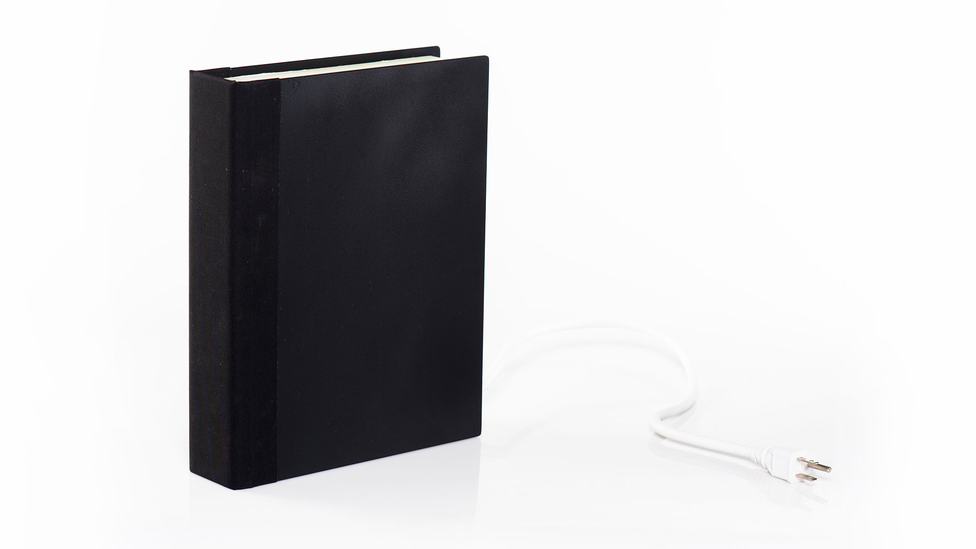 Closed black hardcover book standing with three prong power cord extended to the right