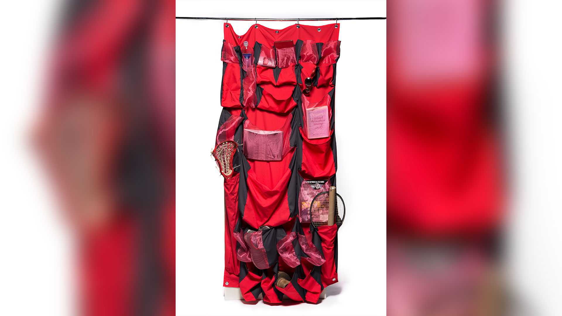 Red curtain on closet pole with front pockets of various sizes with different items inside