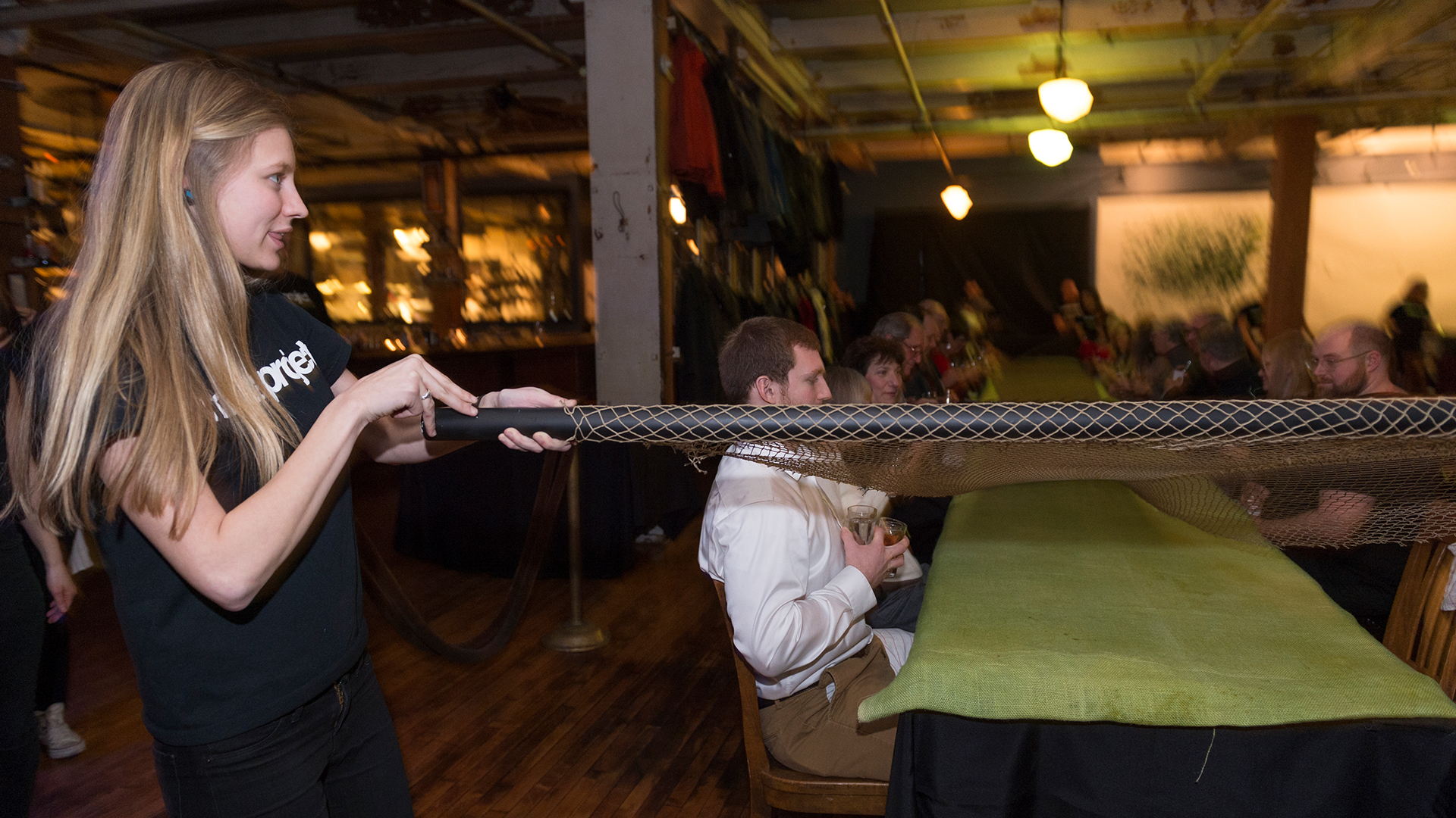 Student walking along side of long table unrolling fabric that lays on top