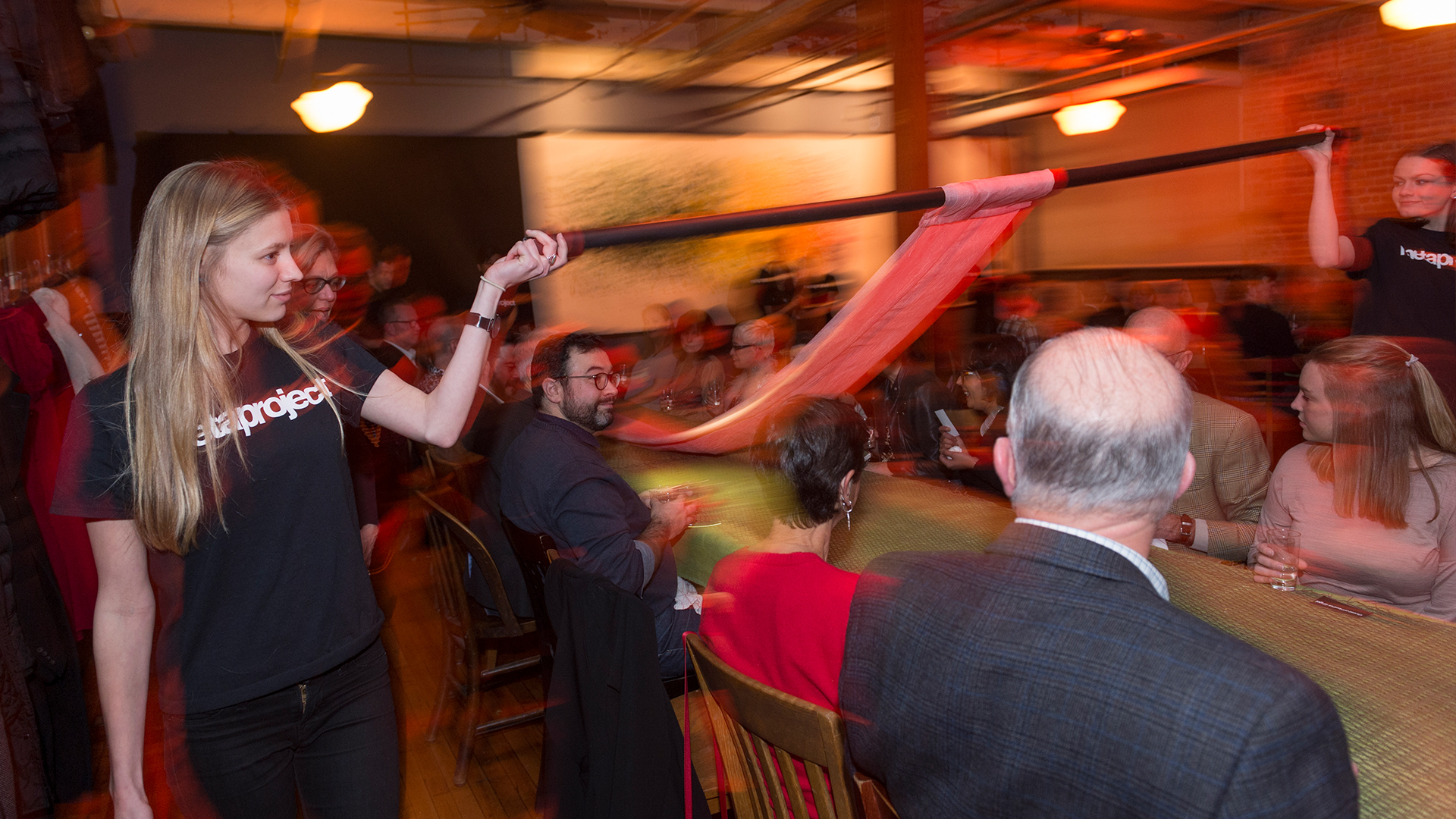 Student walking along side of long table unrolling fabric that lays on top, side view