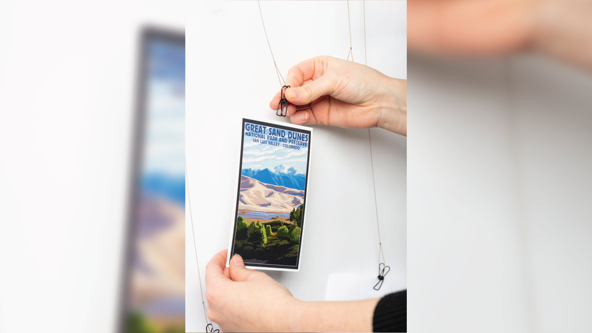 Hands placing a postcard on the hangers.