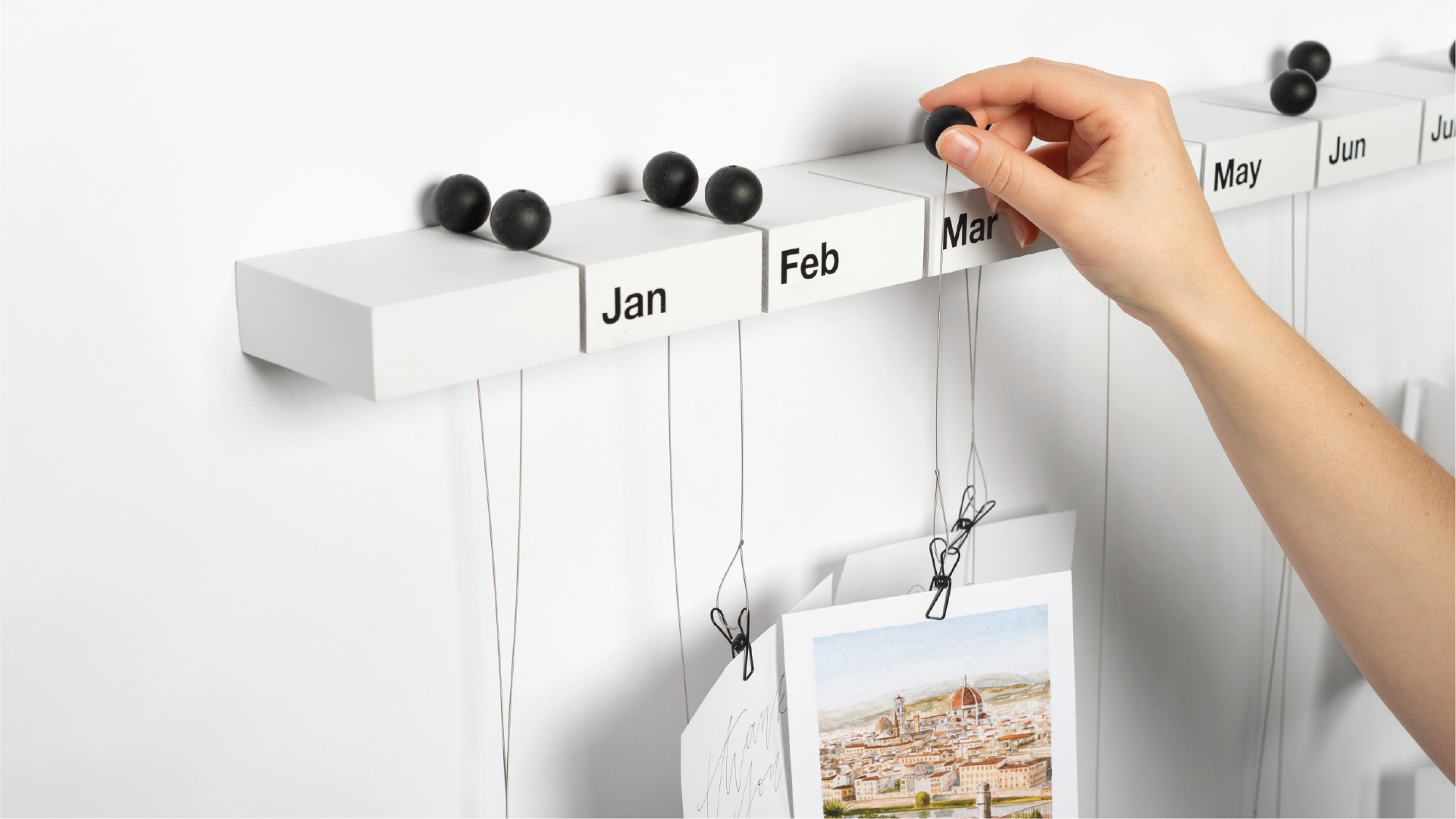 Hands placing the holders on the month slot of the white shelf.
