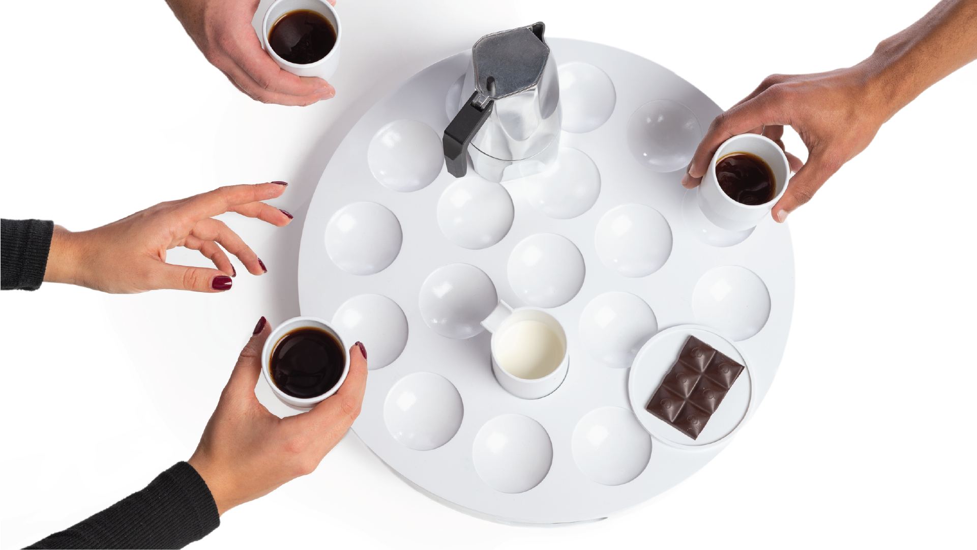 Top view of the coffee set. The set has circular slots on its top surfaces where hands are putting cups on it. There is a tray with food and a kettle on the top of the tray.