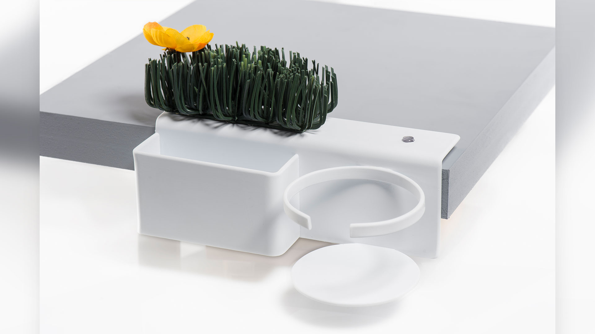 White Deskside shelf attached to side of table top a rectangular slot, fake greenery above slot, a cup holder to the right of slot