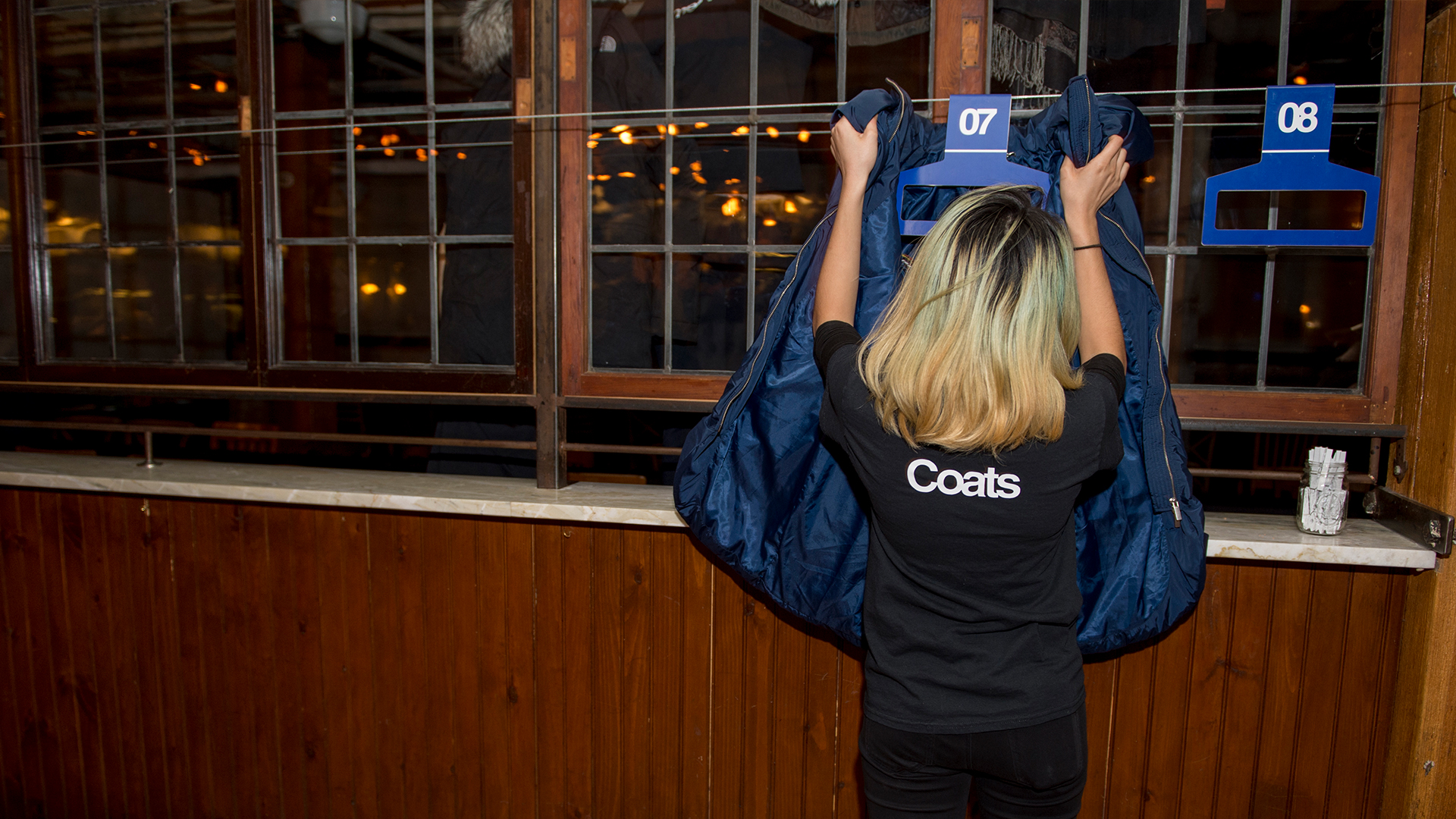 Someone draping coat around coat hanger that slips over suspended wire