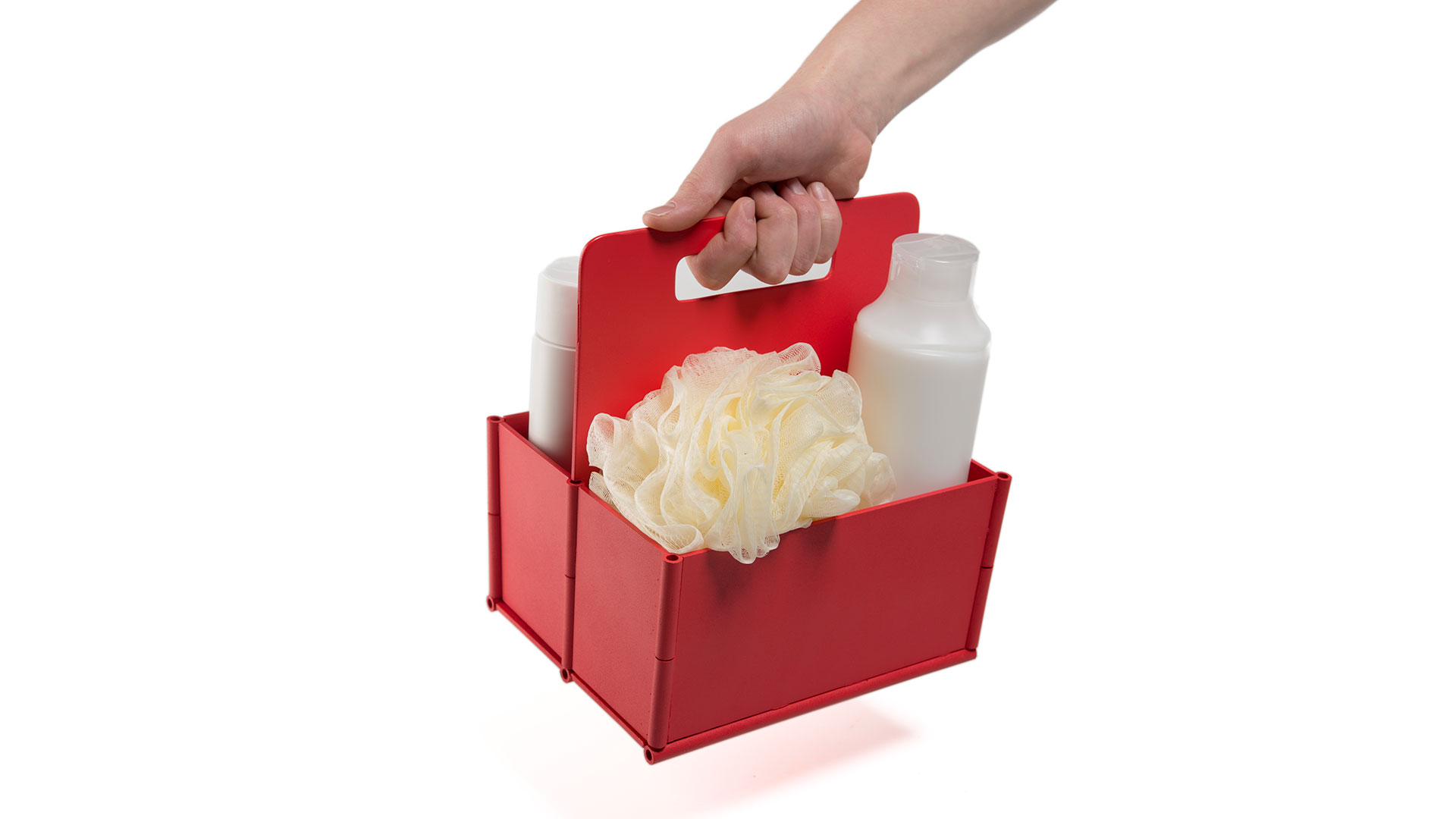 Someone holding red rectangular six pack carrier from center handle with assorted shower items inside including bottles and sponge