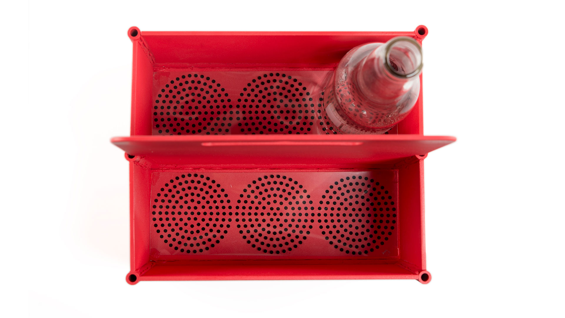 Aerial view of red rectangular carrier with empty glass drinking bottle in top right six pack spot, circular drainage holes under each six pack spot 