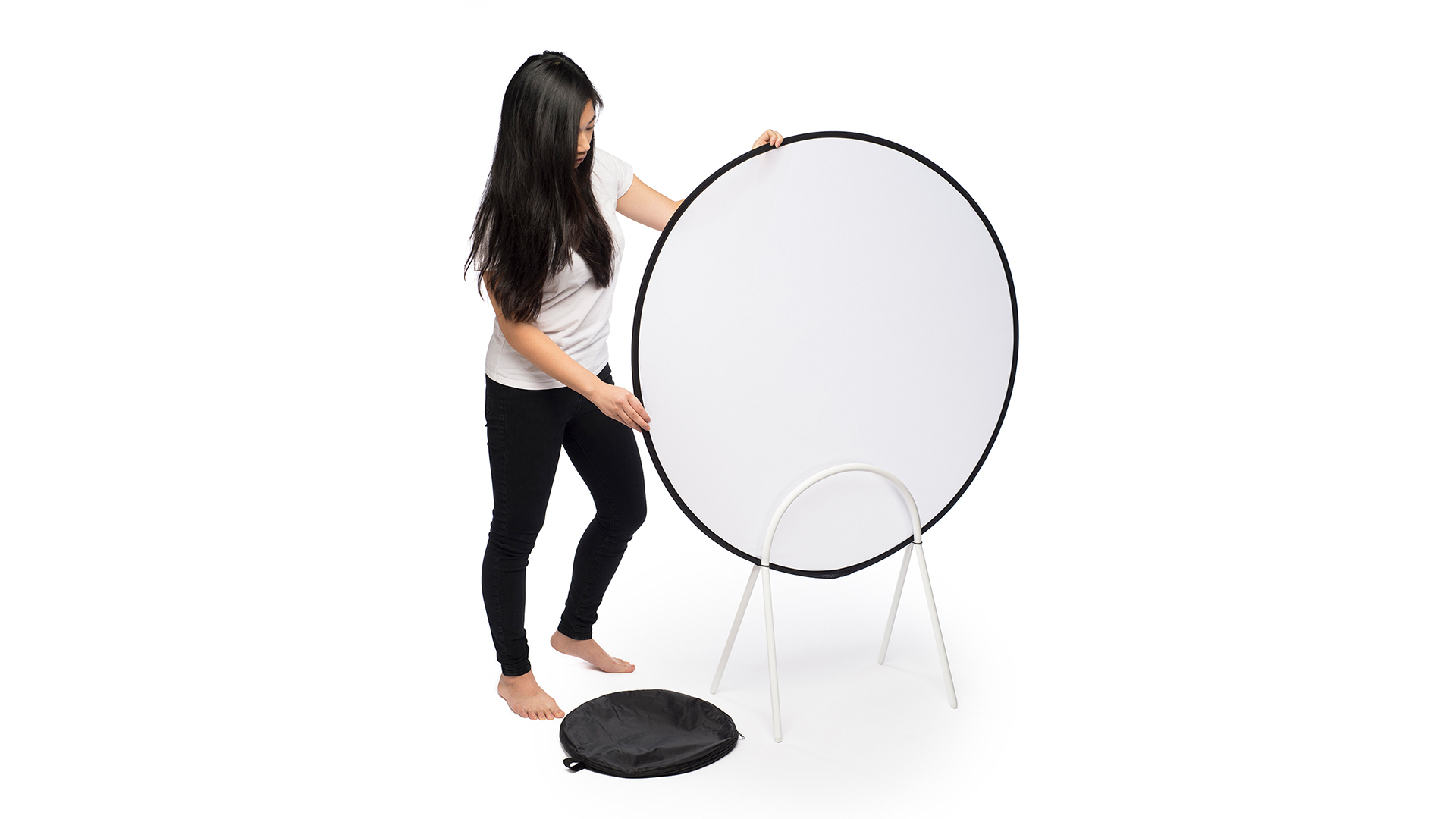 Someone placing white cylindrical space separator into stand with round black bag unzipped on floor