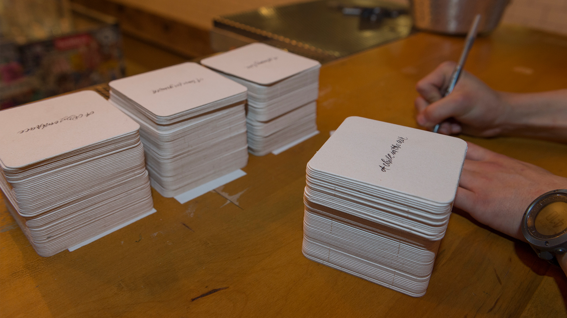 Four large stacks of square white coasters with "A Chill in the Air" in lettering in center