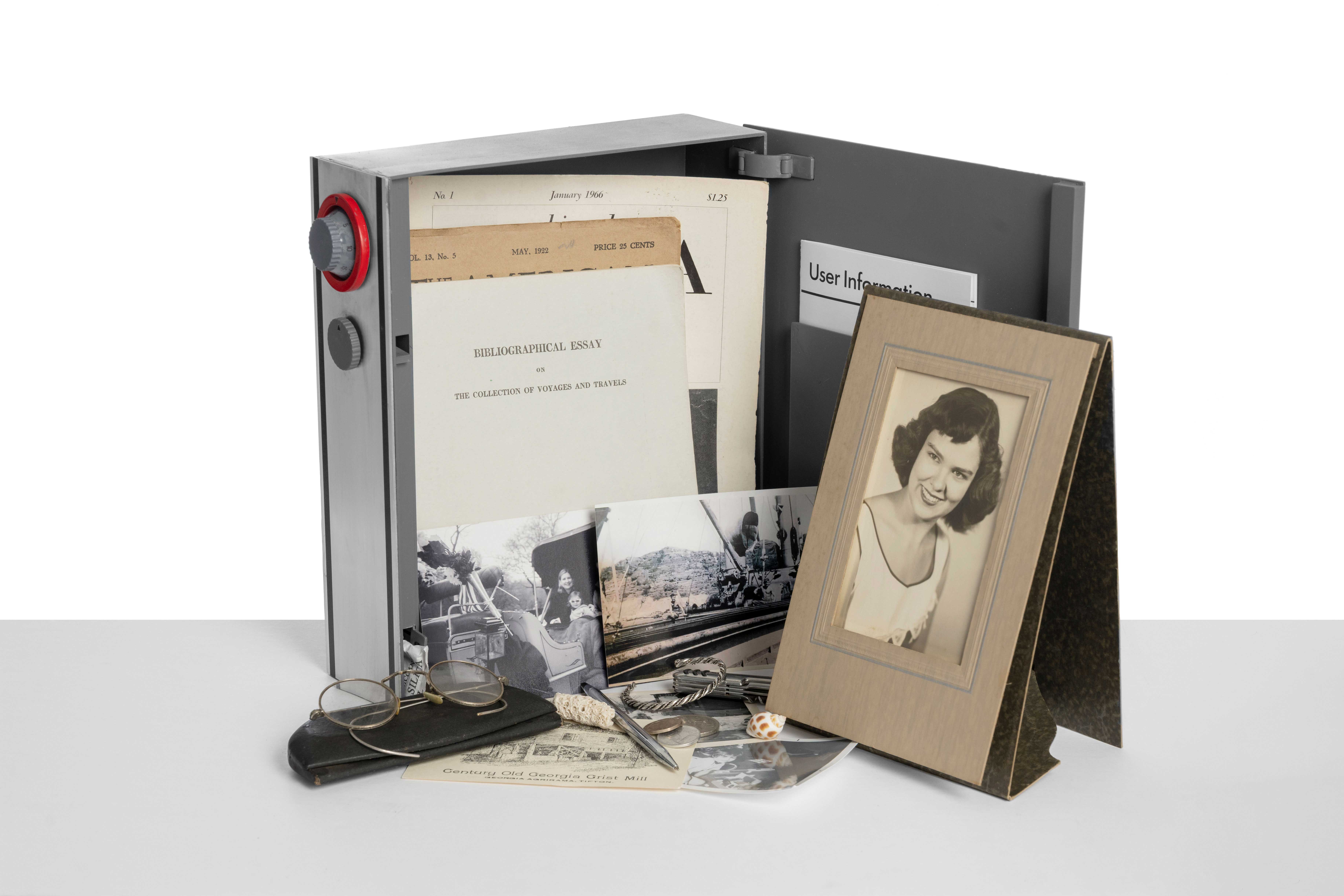 Photo of Capsule model standing open with miscellaneous sentimental items like photos and documents spilling out of it.