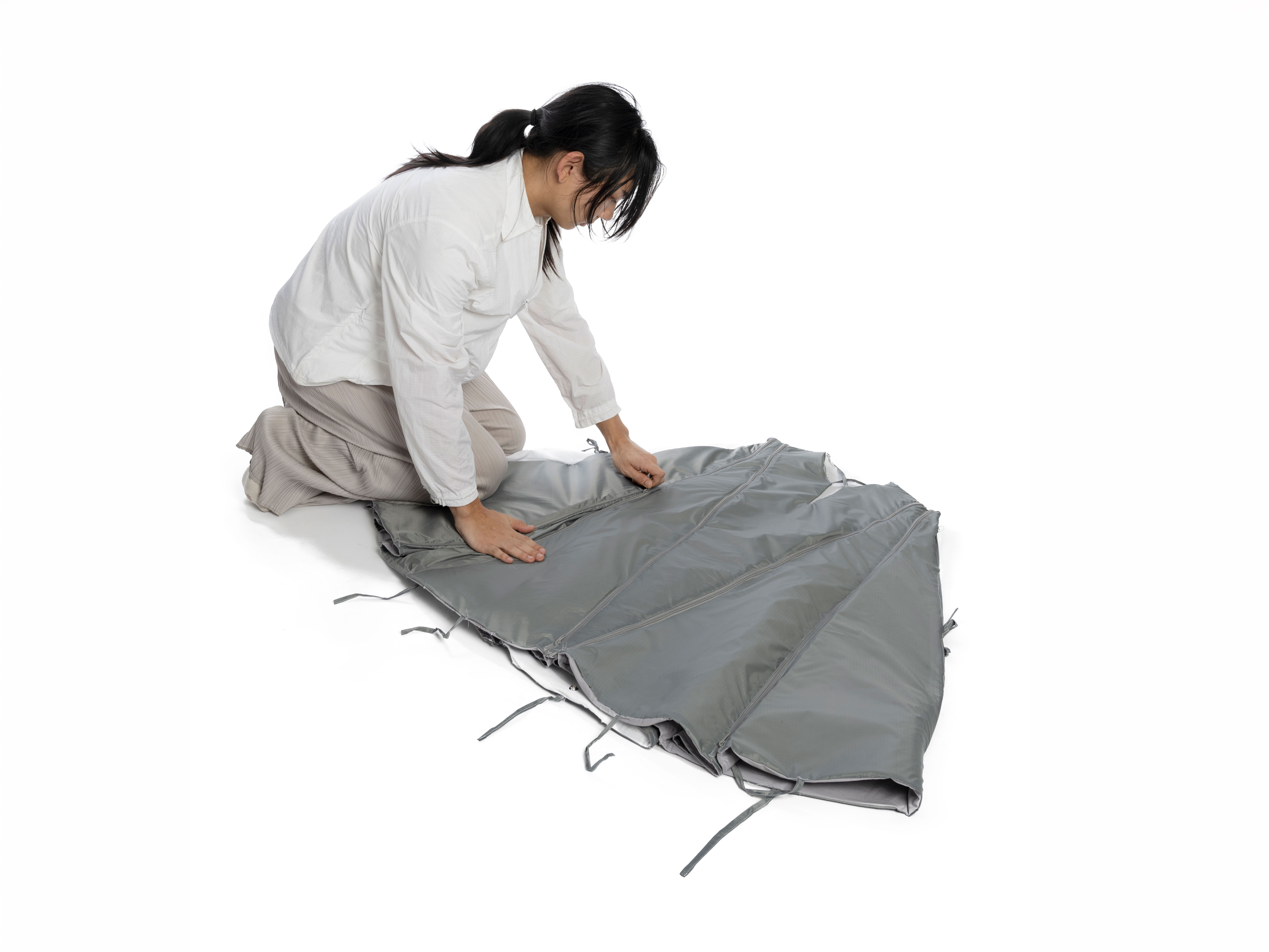 Photo of a women laying out the Cloak model on a white floor. 