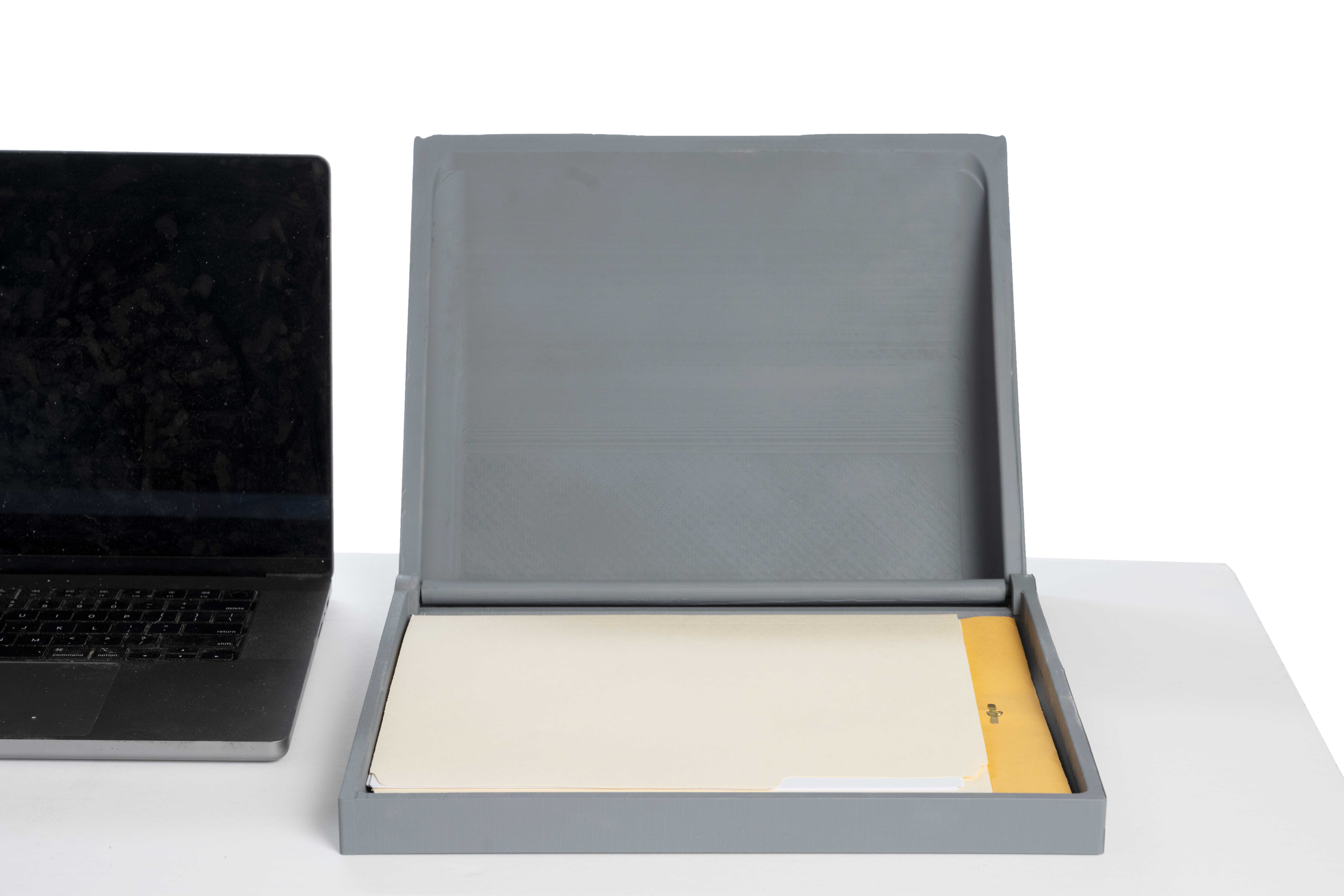Photo of Kee Vault grey model sitting open on a surface next to an apple laptop, with files and folders inside the kee vault model.