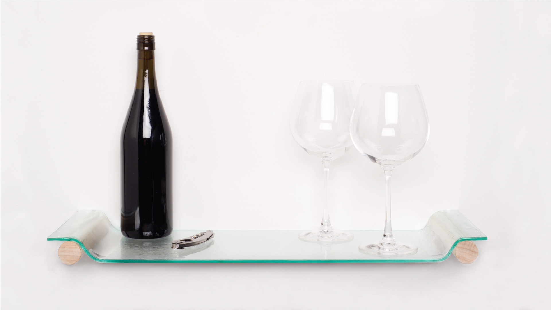 Glass tray placed on the wall. Bottle of wine, 2 cups of wines and a bottle opener placed on the top of the tray.