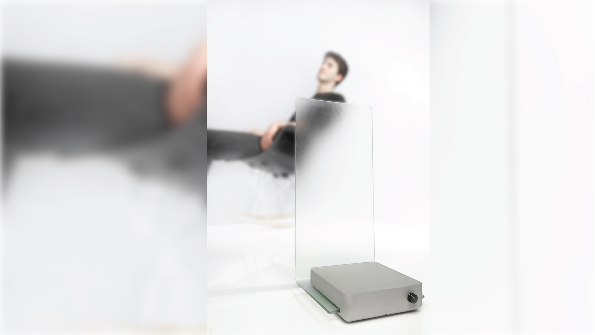 A desktop noise generator in a rectangular format with a  frost glass barrier. Image of a person sitting on a chair on the background.