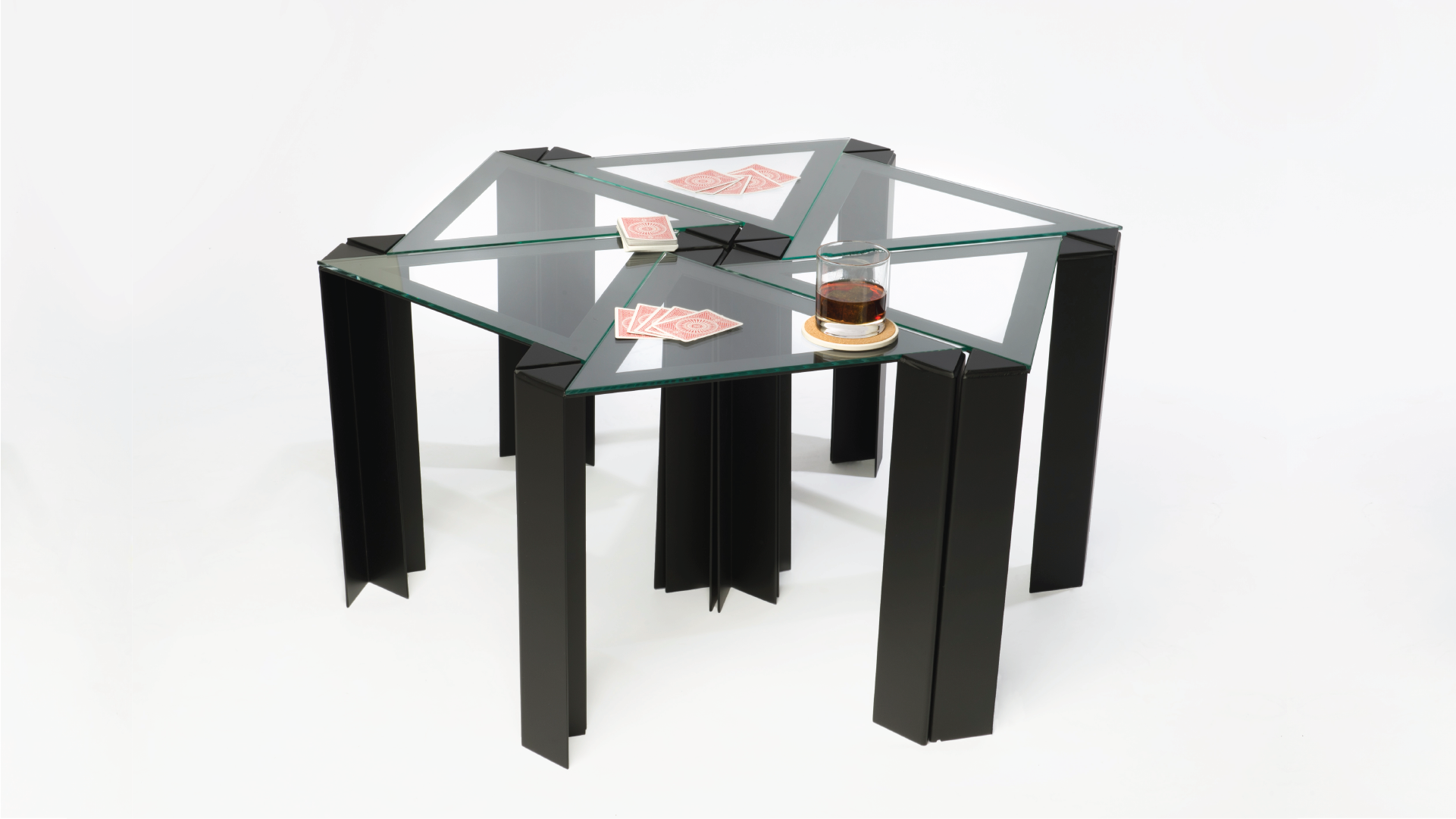 A series of six stainless steel tables in a triangular shape with glass tabletops. The tables are placed closed to each other, forming a bigger one.