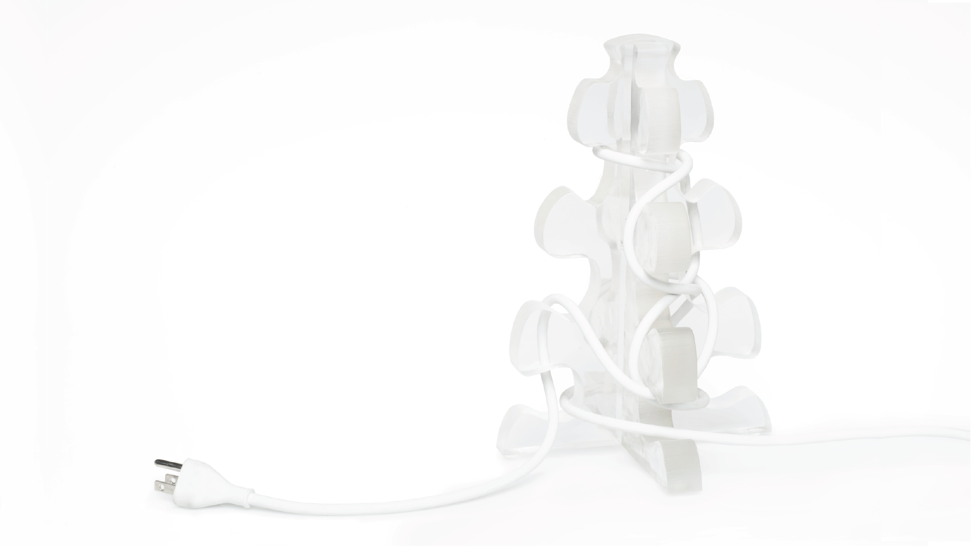 Frost glass cord organizer placed on the floor. A electric cord is wrapped around the product.