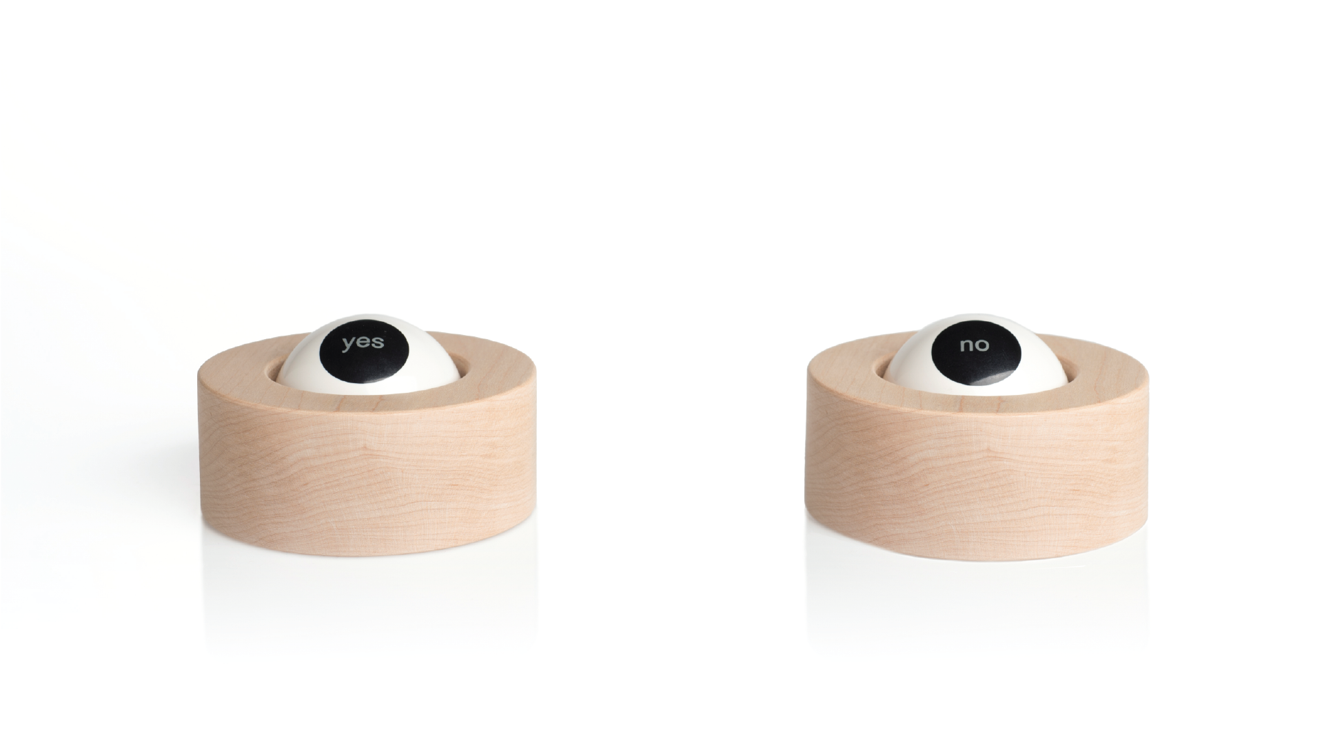 Two wooden blocks in a cylindrical format with a sphere painted like a eye. Inside the iris, one sphere says yes and the second one says no.