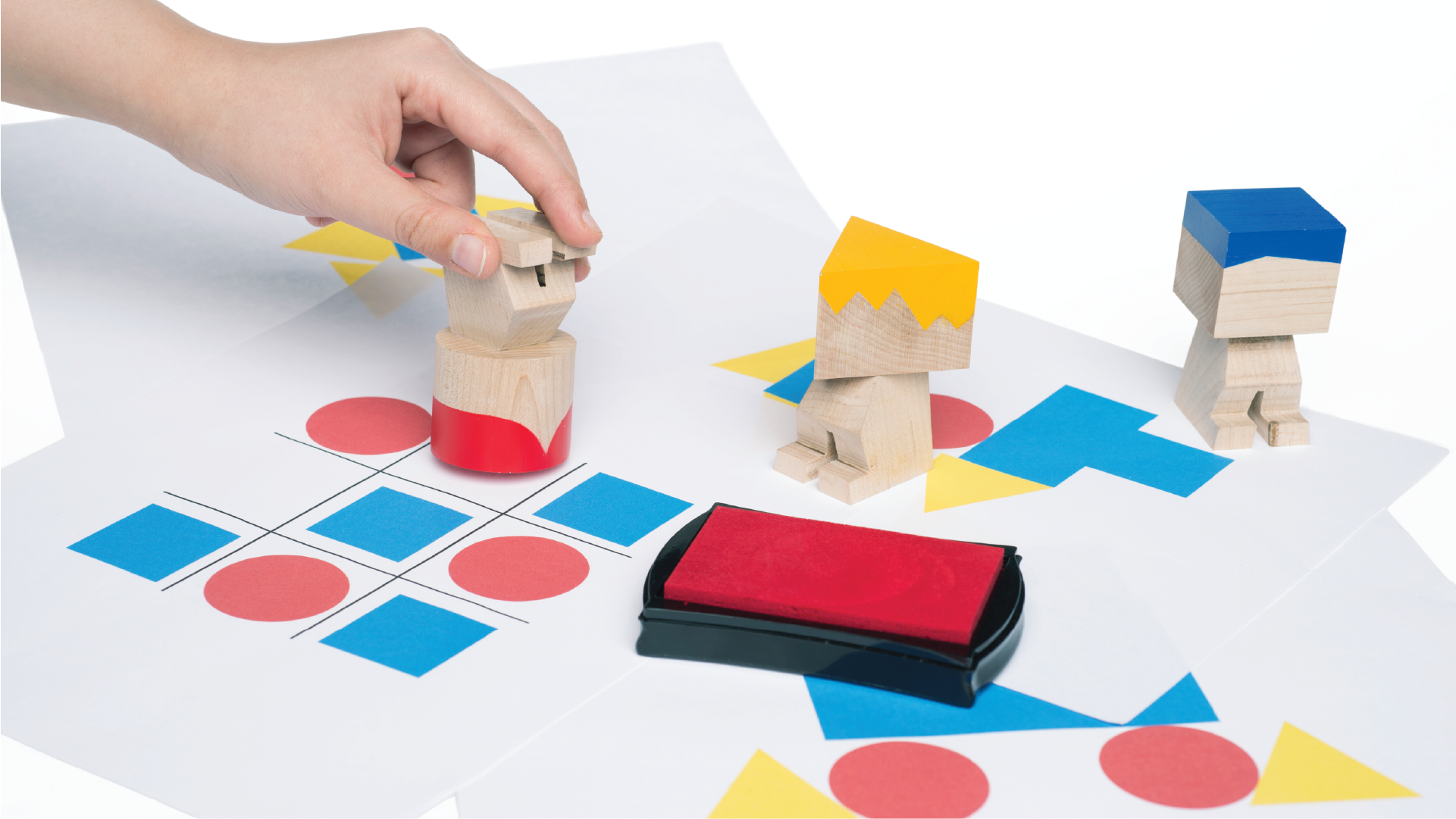 Hand placing the wooden mini figure on a Tic-Tac-Toe set. The other mini figures are place on the corner together with a case.
