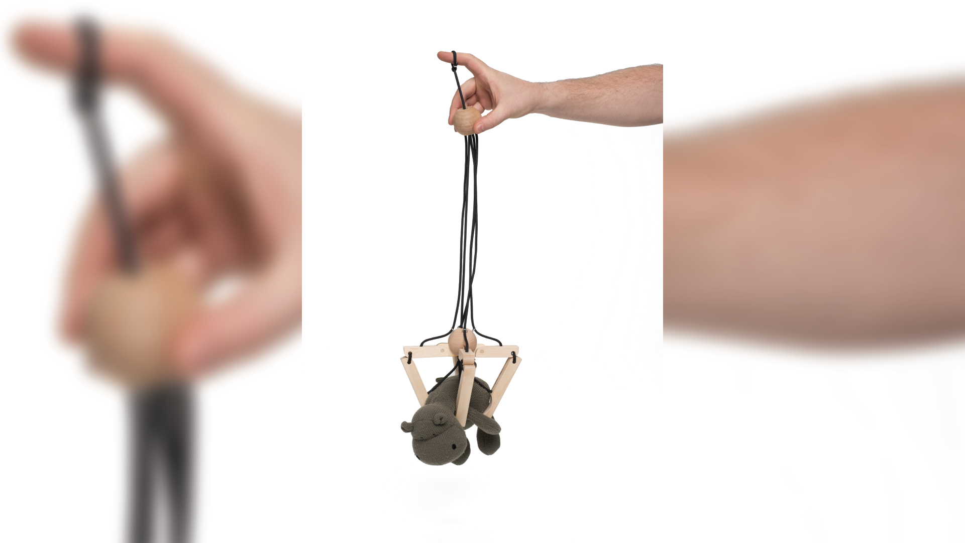 Hand holding the wooden handle and pulling the strings to capture a stuffed animal.