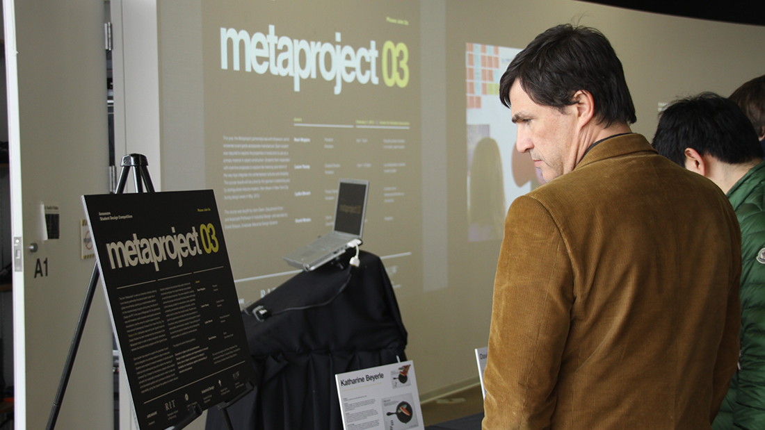 A person reading a metaproject 03 poster place in easels.