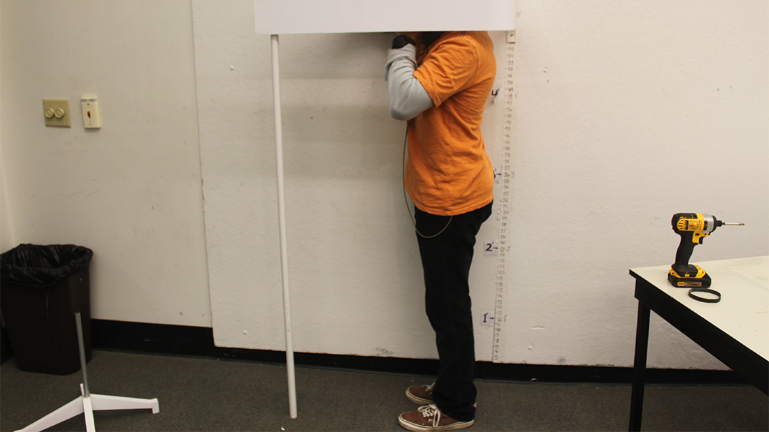 Student at the studio space evaluating prototype's measurements. The student is testing the prototype on themselves.