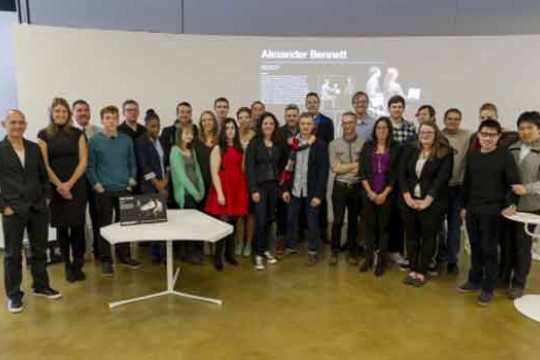 A group of students pose for a photo in front of a projected screen.