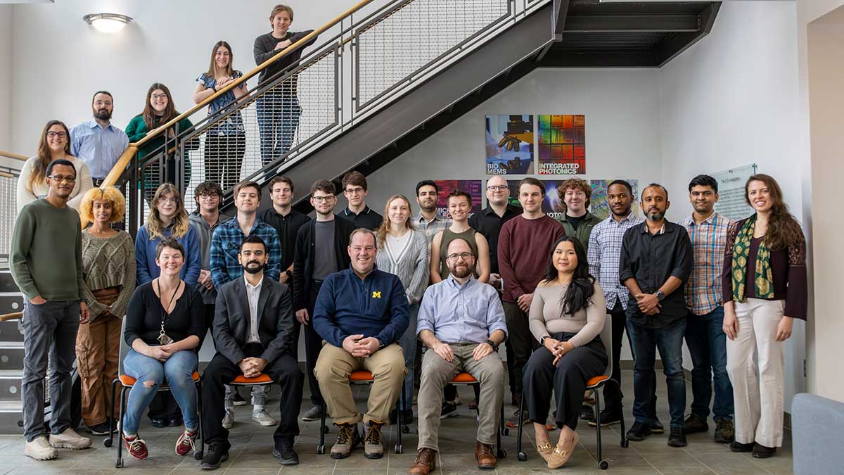 a large group of researchers and student posing in an atrium.