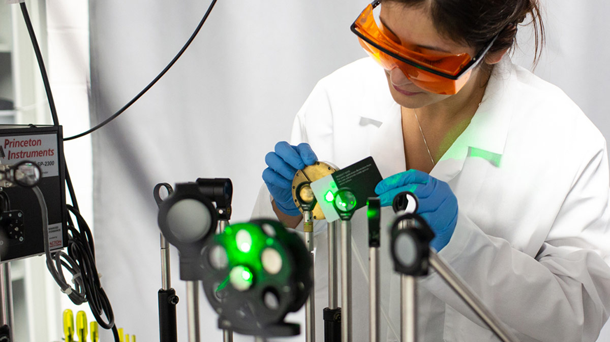 a female researcher adjusting specialized lenses and imaging equipment.
